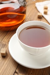 Aromatic black tea and sugar cubes on wooden table, closeup