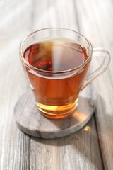Aromatic black tea in glass cup on wooden table, closeup