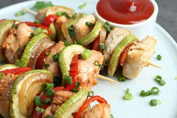 Tasty skewers with chicken, vegetables, sauce and green onion on table, closeup