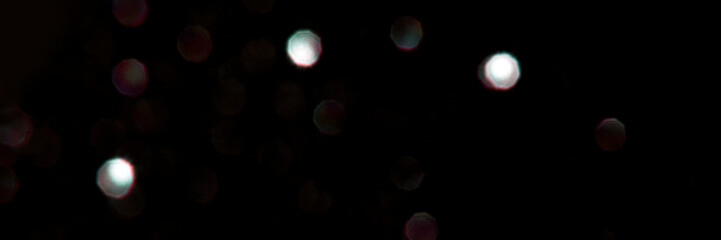 Abstract dark bokeh light pattern with soft, blurred orbs on black background.