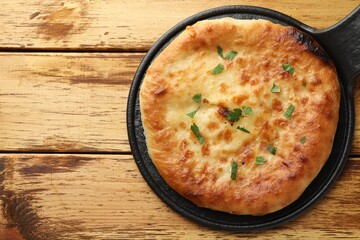 Delicious Megrelian khachapuri with parsley on wooden table, top view. Space for text