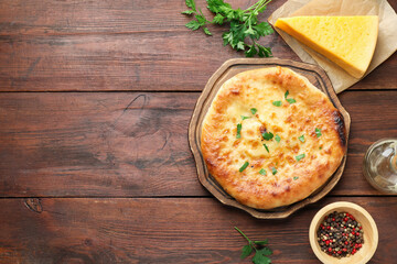 Delicious Megrelian khachapuri with ingredients on wooden table, flat lay. Space for text