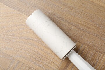 Sticky lint roller on wooden table, top view