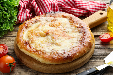 Delicious Megrelian khachapuri and products on wooden table, closeup