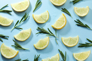 Slices of lemon, rosemary and water drops on light blue background, flat lay