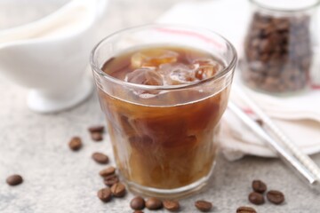 Tasty iced coffee with milk and beans on light table, closeup