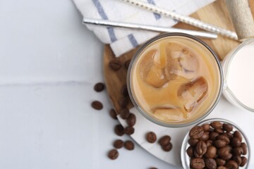 Tasty iced coffee with milk and beans on white tiled table, flat lay. Space for text