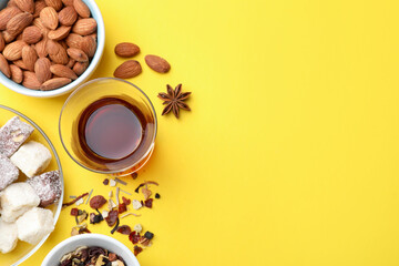 Flat lay composition with traditional Turkish tea, and sweets on yellow background. Space for text