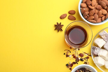 Flat lay composition with traditional Turkish tea, and sweets on yellow background. Space for text