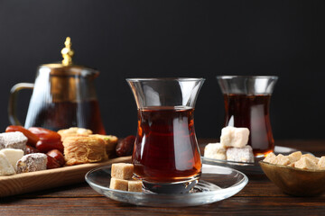 Traditional Turkish tea, brown sugar and sweets on wooden table, closeup