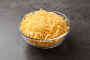 Grated cheese in bowl on grey table, closeup