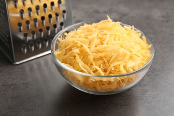 Grated cheese and grater on grey table, closeup