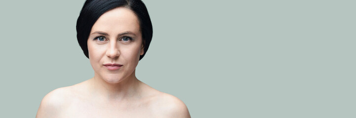 Portrait of caucasian adult female with short black hair against a soft gray background.