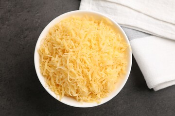 Grated cheese in bowl on grey table, top view