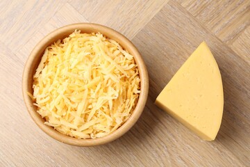 Grated and piece of cheese on wooden table, flat lay