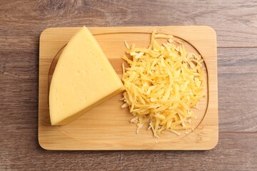 Grated and piece of cheese on wooden table, top view