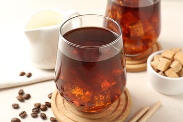 Tasty iced coffee, milk, sugar and beans on white table, closeup