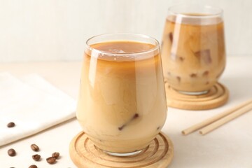 Tasty iced coffee with milk and beans on white table, closeup