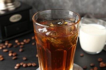 Tasty iced coffee, milk and beans on black table, closeup