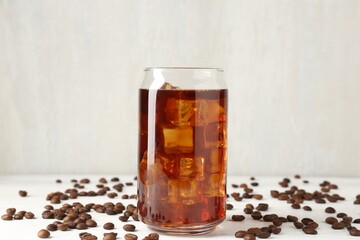 Tasty iced coffee and beans on white wooden table