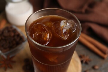 Tasty iced coffee in glass and beans on wooden table, closeup