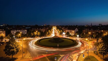 Aerial view of roundabout with light trails at dusk in a european city with trees and buildings