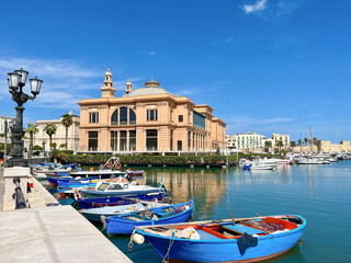 Historisches Theater am Hafen von Bari mit bunten Fischerbooten im Vordergrund, sonniger Himmel und mediterranes Flair an der Adriak&uuml;ste Apuliens