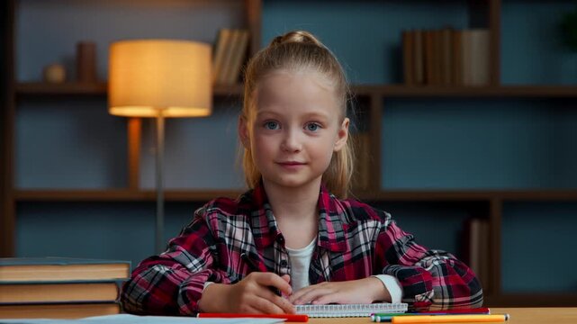 Caucasian girl kid daughter child with color pencils looking at camera nod head yes raising arm ready to answer internet teacher e-learning smiling schoolgirl at evening home draw picture studying