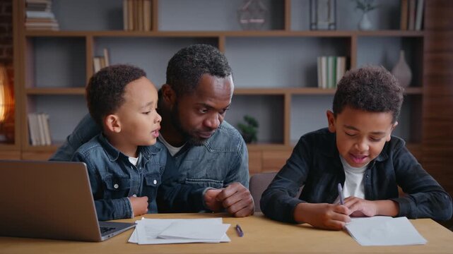 African American family father teaching son at home explaining homework caring dad teach schoolboy pupil helping with e-learning studying daddy with two little boys sons children kids with laptop