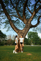 Women friends relaxing by large tree in park
