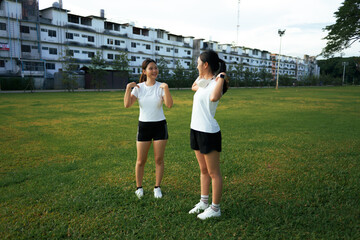 Two Asian women exercising stretching outdoors in park