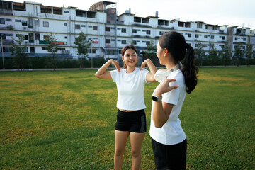 Two women stretching talking and smiling in park