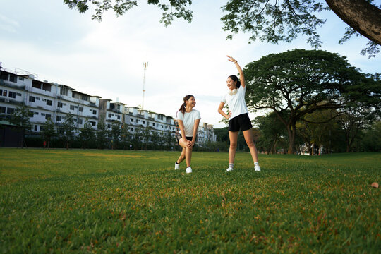 Women friends exercising stretching in green urban park