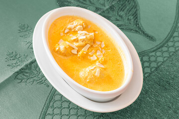 Poulet Shahi Korma – curry crémeux au poulet avec amandes et noix de cajou, plat indien traditionnel servi sur nappe verte. Cuisine indienne.