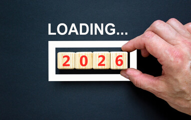 Business concept of 2026 loading new year symbol. Wooden cubes with words 2026 loading. Beautiful black background. Businessman's hand. Business 2026 loading happy new year concept. Copy space.