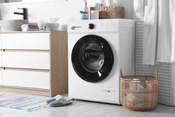 Washing machine and laundry basket near sink in bathroom. Interior design