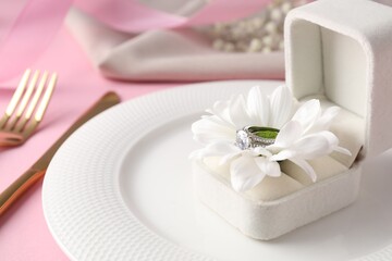 Beautiful table setting for romantic dinner and box with engagement ring on pink background, closeup