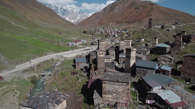 Aerial drone footage of Ushguli village in Georgia, one of the highest inhabited places in the world. Stone Svan towers and houses surrounded by majestic snow-capped Caucasus mountains in summer