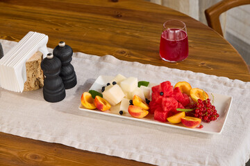 A Beautifully Vibrant Fresh Fruit Platter Accompanied by a Beverage on a Wooden Table