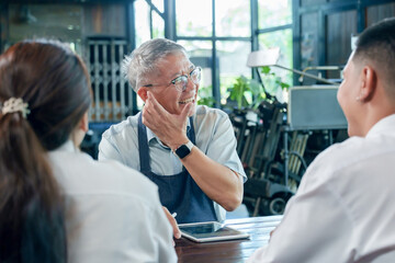 Obraz premium Elderly asian man cafe owner smiling while talking with young employee during business meeting teamwork discussion partnership management small business friendly communication lifestyle entrepreneur