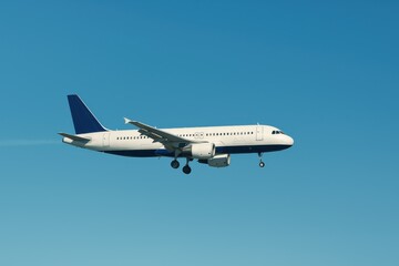 Obraz premium Commercial Jet Airplane Flying Through Clear Blue Sky Ready for Landing