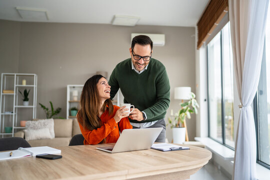 Happy couple enjoying coffee while working remotely at home