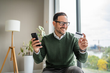 Man making secure online payment using smart phone and credit card