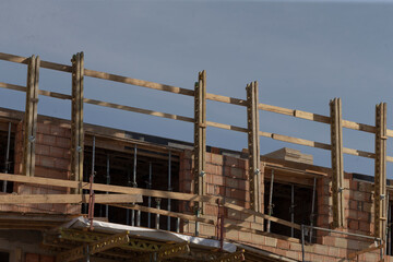 upper level deck with safety rails and large window openings overlooking worksite, exposed brick edges and temporary wooden barriers create gritty construction detail and daytime industrial mood