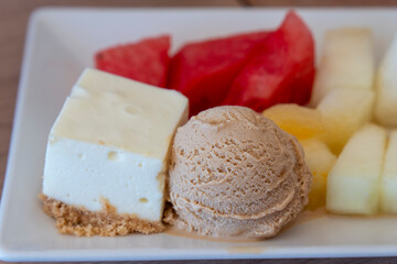 Plate with assorted desserts in a restaurant: melon, sweets, and ice cream