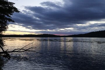 A panoramic view of a sunset over a wilderness lake in the Adirondacks with red and gold colors.