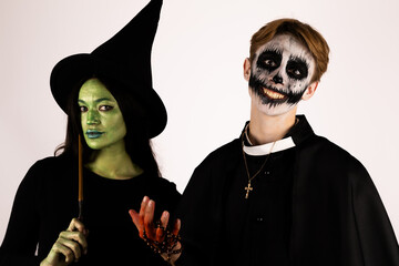 Man and woman in witch costumes surrounded by pumpkins and spider webs