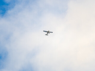 Small ultralight airplane with overhead wing and single propeller flying in sunset sky.