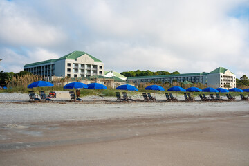 Beachside resort with blue umbrellas and lounge chairs during a cloudy day
