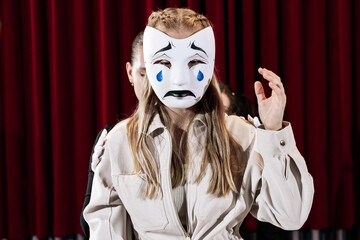 A mime artist on stage wearing a mask, close-up.